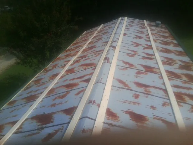 Rusted metal roof panels with new wood purlins before replacement — Storm Damage Roof Repair in Windsor Heights by Roofing Brothers