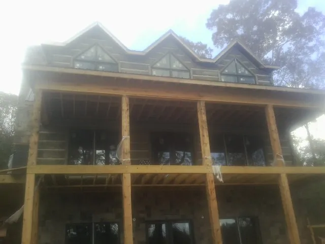 Dormers and porch framing on a large log home under construction — Roof Coating work by our crew in Windsor Heights