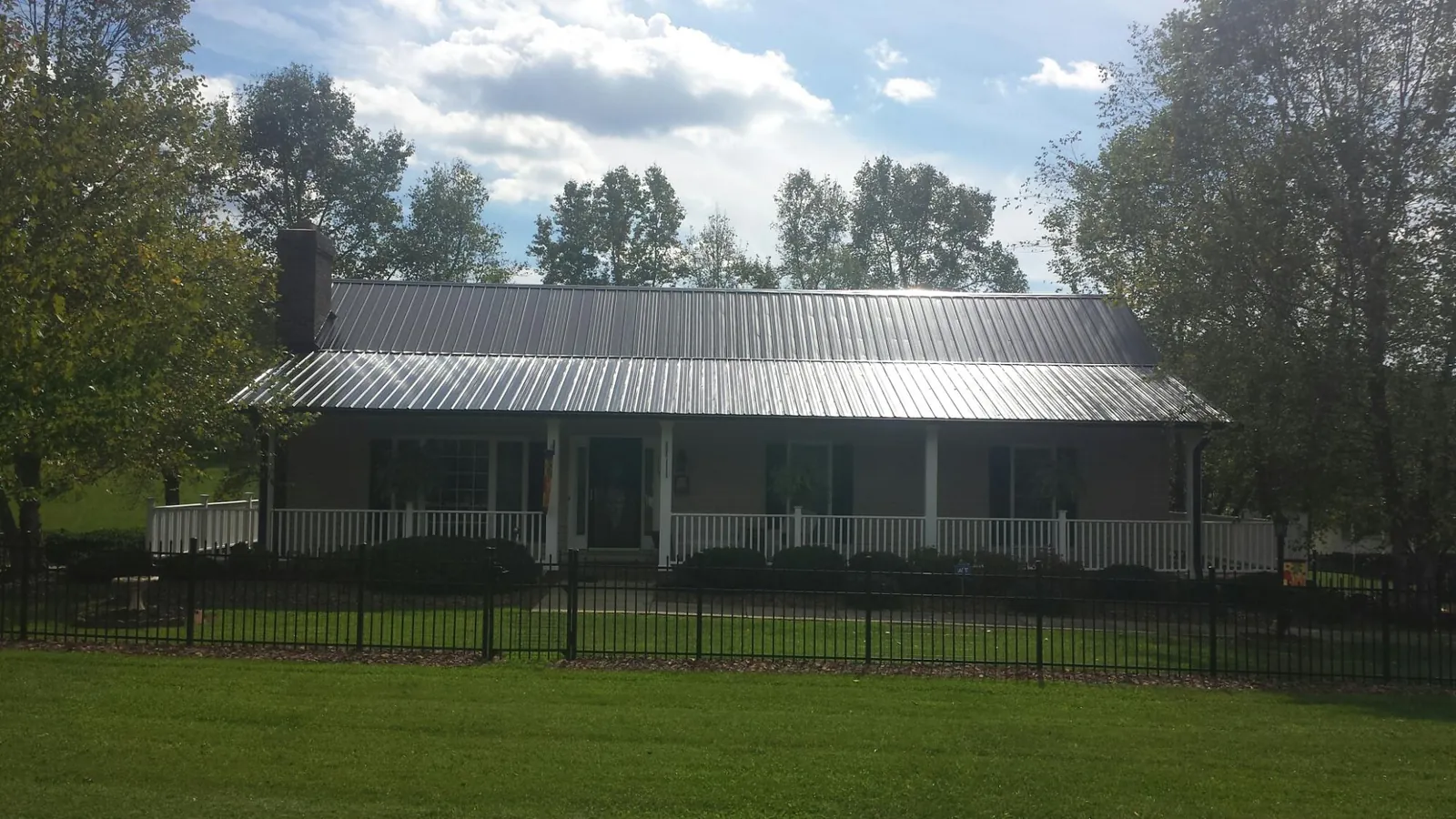 Gray metal roof on a brick ranch with a full width front porch — Gutter Guard Installation work by our crew in Windsor Heights