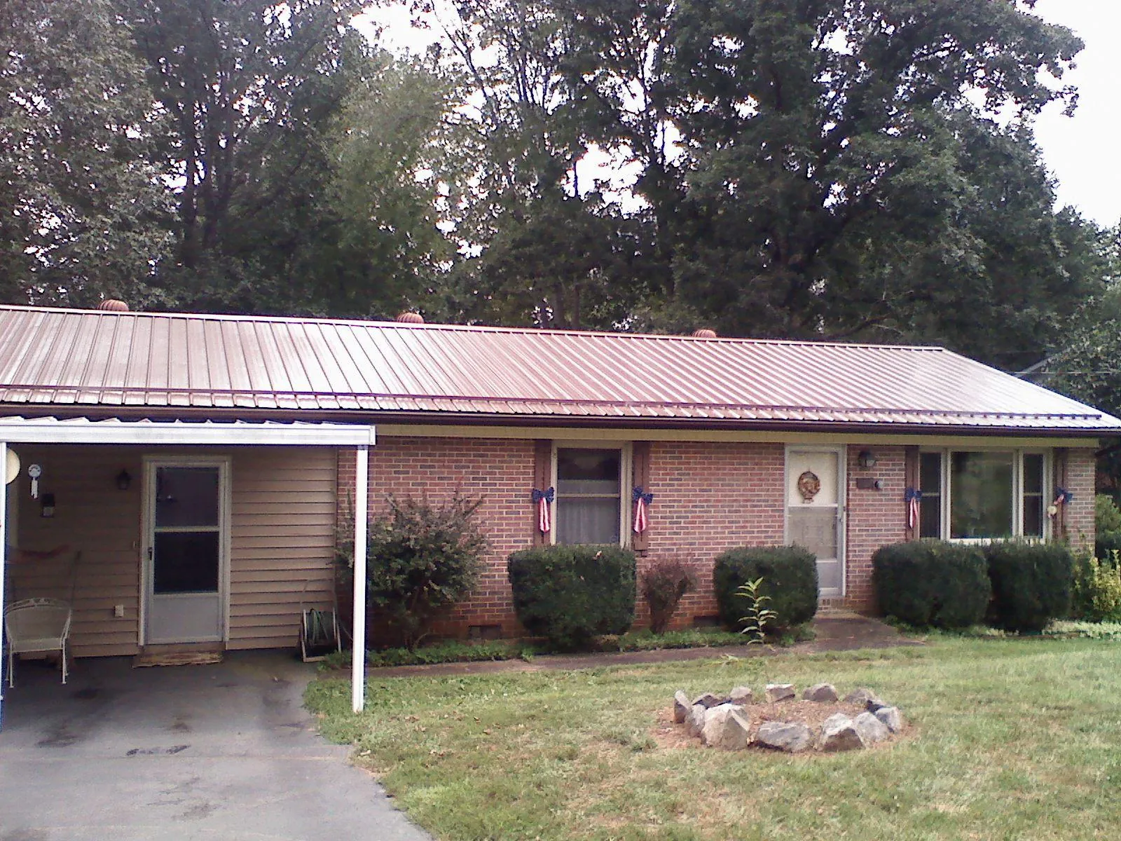 Bronze metal roof and carport on a brick ranch home — Roof Repair work by our crew in Windsor Heights