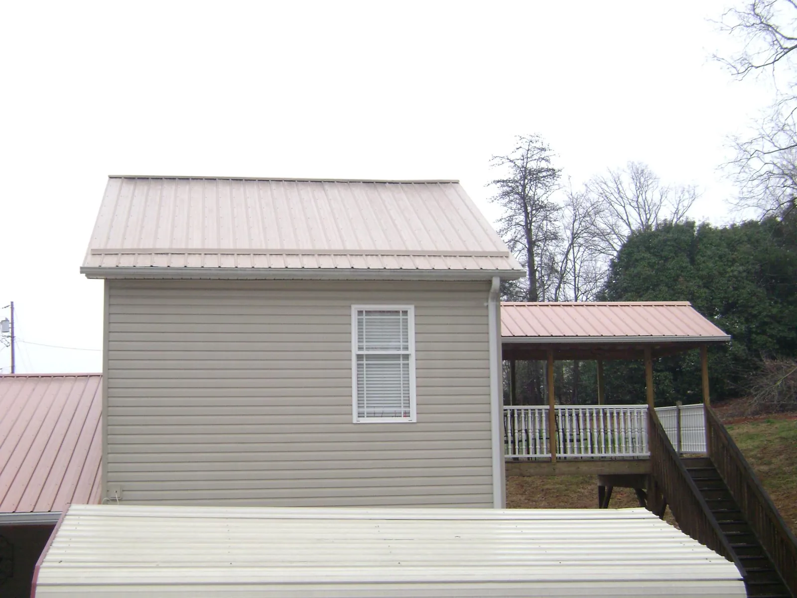 Tan metal roofs on a two story addition and attached porch, from a Roof Replacement job in Windsor Heights